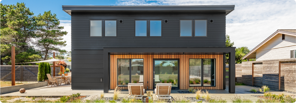 Back of a black home on a sunny day with patio