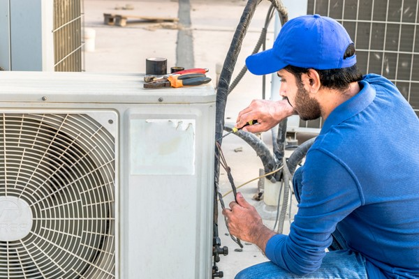 worker repairing air conditioner unit