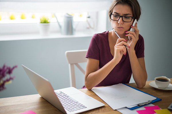 person on phone and computer filling out papers