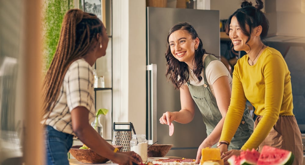 three women smiling and laughing around a table