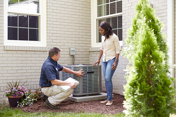 HVAC professional speaking with a homeowner near an outdoor air conditioning system