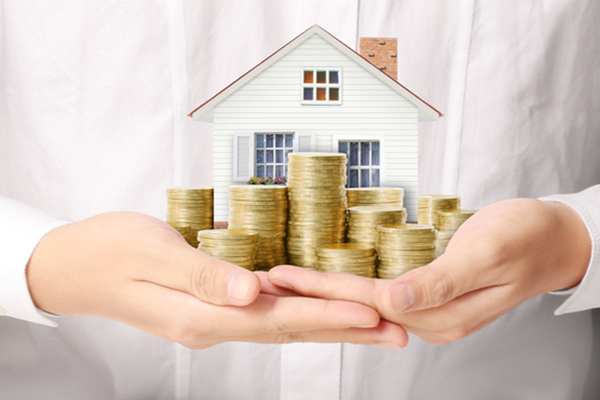 holding model house surrounded by coins