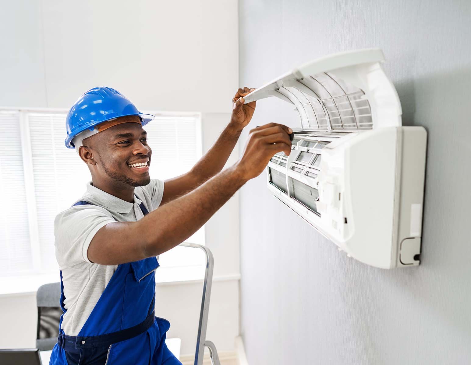 Smiling technician repairing an air conditioner.