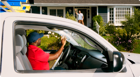 person in car waving at person in house