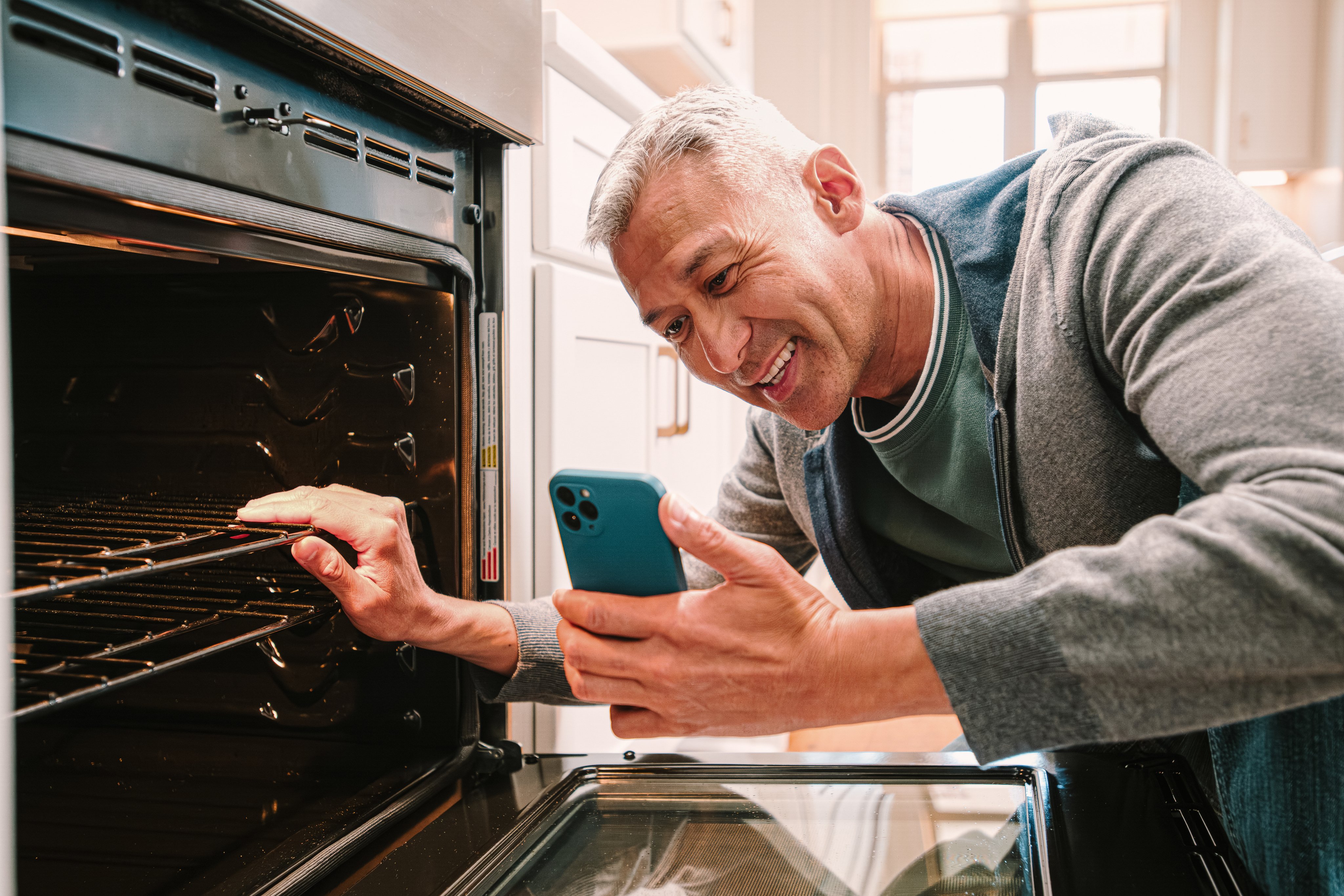Customer video chatting on phone in front of open oven