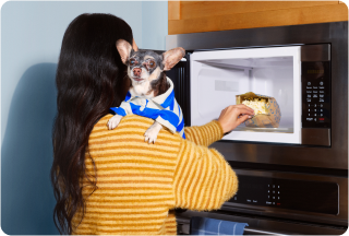 Person holding dog opening microwave
