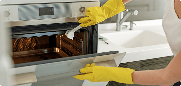Scrubbing inside of oven with rubber gloves on